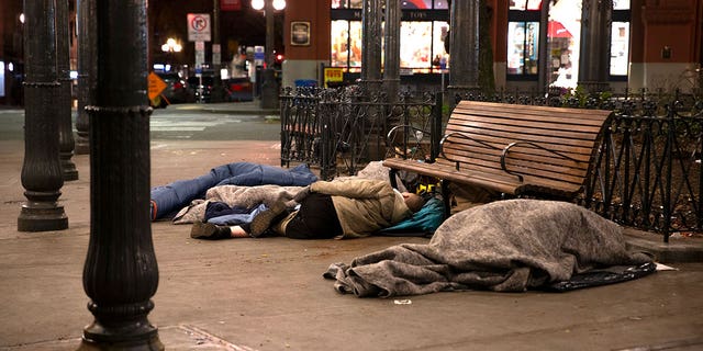 People sleep outside on a sidewalk on April 6, 2020 in Seattle. (Photo by Karen Ducey/Getty Images)