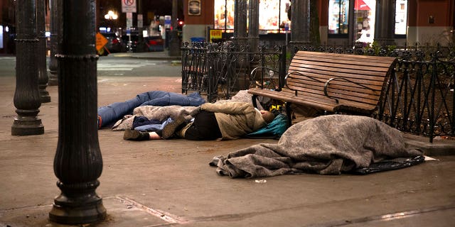 People sleep outside on a sidewalk on April 6, 2020 in Seattle. (Photo by Karen Ducey/Getty Images)