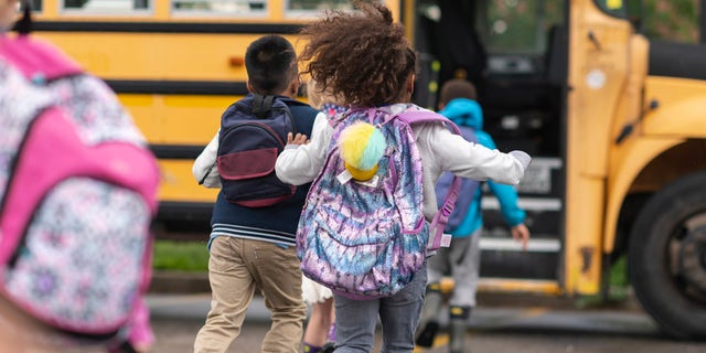 Children run toward their school bus. All too often, kids' backpacks seem like an innocent back-to-school item, suggested one doctor; yet heavy backpacks can create medical issues with youngsters' spines and necks. 