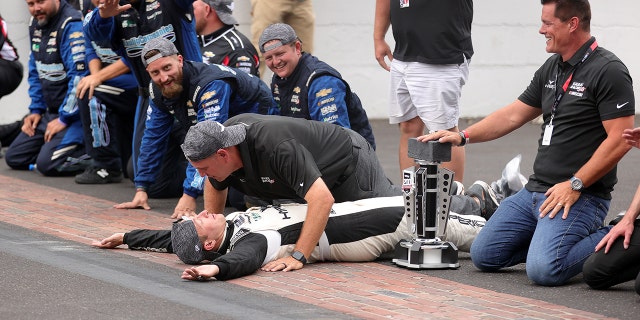 AJ Allmendinger, driver celebrates with his team on Indy's Yard of Bricks.