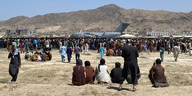 Hundreds of people gather near a U.S. Air Force C-17 transport plane at a perimeter at the international airport in Kabul, Afghanistan, on Monday, Aug. 17, 2021