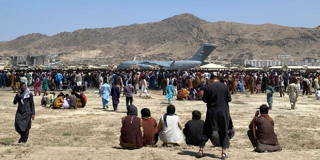 Hundreds of people gather near a U.S. Air Force C-17 transport plane at a perimeter at the international airport in Kabul, Afghanistan, in August 2021. 