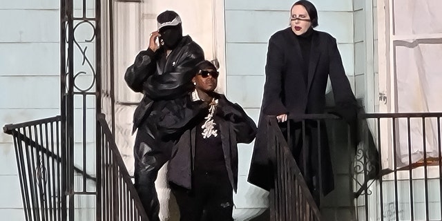 From left, a masked Kanye West, DaBaby and Marilyn Manson hang out on the stoop of a replica of the house of West's late mother Donda, at Soldier Field in Chicago, Aug. 26, 2021. (Brian Prahl/MEGA)