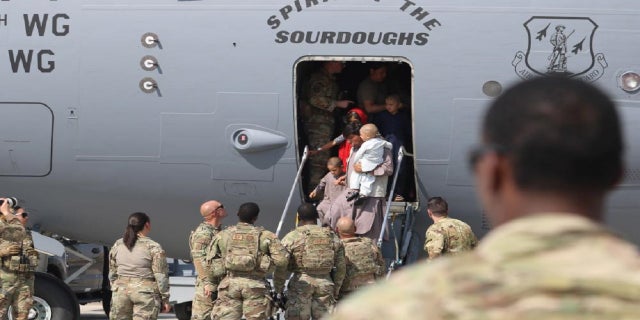 U.S. Air Force Airmen welcome Afghanistan evacuees arriving at Ali Al Salem Air Base in Kuwait on Monday. (U.S. Army Photo by 1st Lt. James Mason/DVIDS)