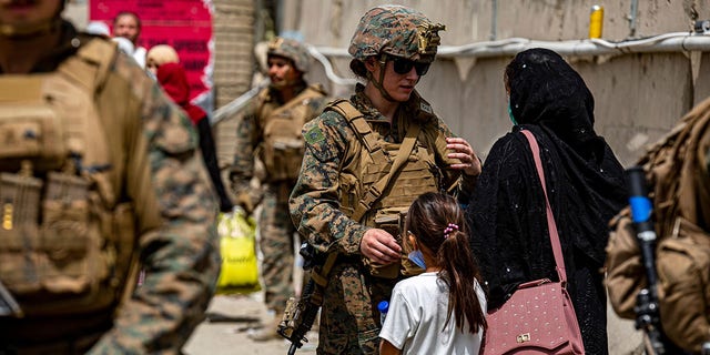 A  @USMC  Marine assists a woman and child during an evacuation at Hamid Karzai International Airport in Kabul, Afghanistan. #HKIA