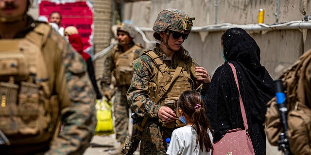 A  @USMC  Marine assists a woman and child during an evacuation at Hamid Karzai International Airport in Kabul, Afghanistan. #HKIA