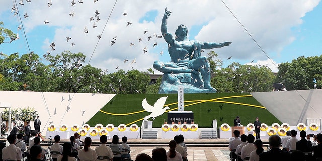 Doves fly over the Statue of Peace during a ceremony at Nagasaki Peace Park in Nagasaki, southern Japan Monday, Aug. 9, 2021. The Japanese city of Nagasaki on Monday marked its 76th anniversary of the U.S. atomic bombing. (Kyodo News via AP)