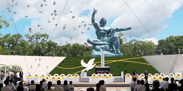 Doves fly over the Statue of Peace during a ceremony at Nagasaki Peace Park in Nagasaki, southern Japan Monday, Aug. 9, 2021. The Japanese city of Nagasaki on Monday marked its 76th anniversary of the U.S. atomic bombing. (Kyodo News via AP)