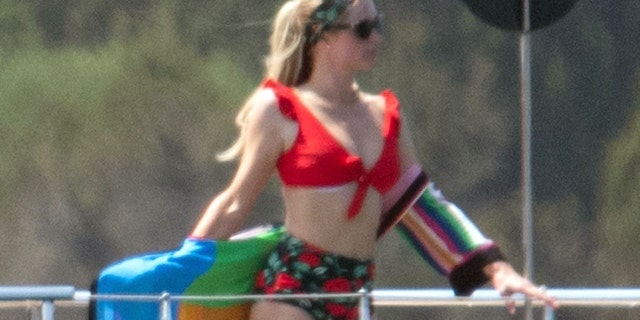 Paris Hilton sported a high-waisted red and floral bikini and sported a striped coverup on a luxurious yacht.