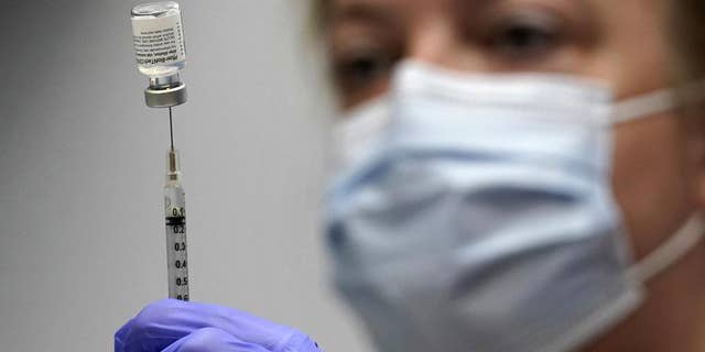 In this March 2, 2021 file photo, a pharmacy technician loads a syringe with Pfizer's COVID-19 vaccine at the Portland Expo in Portland, Maine. 