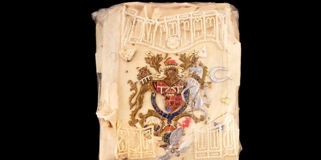  The wedding cake slice has a coat-of-arms design colored in red, silver, gold and blue. It also features a small silver horseshoe and leaf spray with white decorative icing. (Dominic Winter Auctioneers via AP)