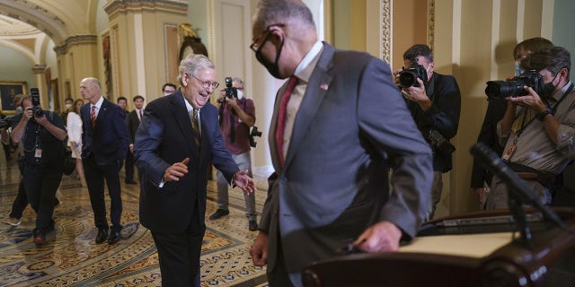 Democratic Senate Leader Chuck Schumer, of New York, and Republican Senate Leader Mitch McConnell, of Kentucky, left-back, enjoy a brief bipartisan moment when they both arrive at the same time to speak to the reporters on the progress of the infrastructure bill, on Capitol Hill in Washington, Tuesday, August 3, 2021. 