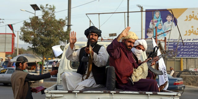 Taliban fighters wave from the back of a pickup truck, in Kabul, Afghanistan, Monday, Aug. 30, 2021. (AP Photo/Khwaja Tawfiq Sediqi)