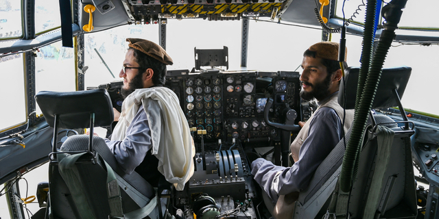 Taliban fighters sit in the cockpit of an Afghan Air Force aircraft at the airport in Kabul on August 31, 2021, after the US has pulled all its troops out of the country to end a brutal 20-year war -- one that started and ended with the hardline Islamist in power. (Photo by Wakil KOHSAR / AFP) (Photo by WAKIL KOHSAR/AFP via Getty Images)