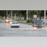 Vehicles drive through Hurricane Ida storm surge floodwater at U.S. 90 and Miramar Avenue in Biloxi, Miss., Sunday, Aug. 29, 2021. The Honda Civic, stalled out in the middle of the street as it tried to drive through the water. (Justin Mitchell/The Sun Herald via AP)