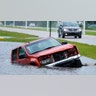 An abandoned vehicle is half submerged in a ditch next to a near flooded highway as the outer bands of Hurricane Ida arrive Sunday, Aug. 29, 2021, in Bay Saint Louis, Miss. (AP Photo/Steve Helber)