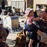 In this image provided by the U.S. Marine Corps, a marine assigned to Special Purpose Marine Air-Ground Task Force-Crisis Response-Central Command holds a child while her mother is searched, at Hamid Karzai International Airport, Monday, Aug. 23, 2021. (1stLt. Mark Andries/U.S. Marine Corps via AP)