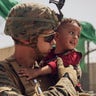In this photo provided by the U.S. Marine Corps, a U.S. Marine with the 24th Marine Expeditionary Unit calms a crying toddler during an evacuation at Hamid Karzai International Airport, Kabul, Afghanistan, Sunday, Aug. 22, 2021. (Staff Sgt. Victor Mancilla/U.S. Marine Corps via AP)