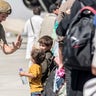 In this image provided by the U.S. Marine Corps, a Marine with Special Purpose Marine Air-Ground Task Force-Crisis Response-Central Command greets children during an evacuation at Hamid Karzai International Airport in Kabul, Afghanistan, Tuesday, Aug. 24, 2021. (Sgt. Samuel Ruiz/U.S. Marine Corps via AP)