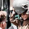 In this Aug. 22, 2021, photo provided by the U.S. Marines, a Marine assigned to Special Purpose Marine Air-Ground Task Force – Crisis Response – Central Command hands a helmet to a child awaiting evacuation at Hamid Karzai International Airport in Kabul, Afghanistan. (Gunnery Sgt. Melissa Marnell/U.S. Marine Corps via AP)