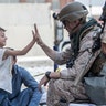 A Marine with Special Purpose Marine Air-Ground Task Force-Crisis Response-Central Command (SPMAGTF-CR-CC) gives a high five to a child during an evacuation at Hamid Karzai International Airport, Kabul, Afghanistan, Aug. 22. U.S. service members are assisting the Department of State with an orderly drawdown of designated personnel in Afghanistan. (U.S. Marine Corps photo by Sgt. Samuel Ruiz).