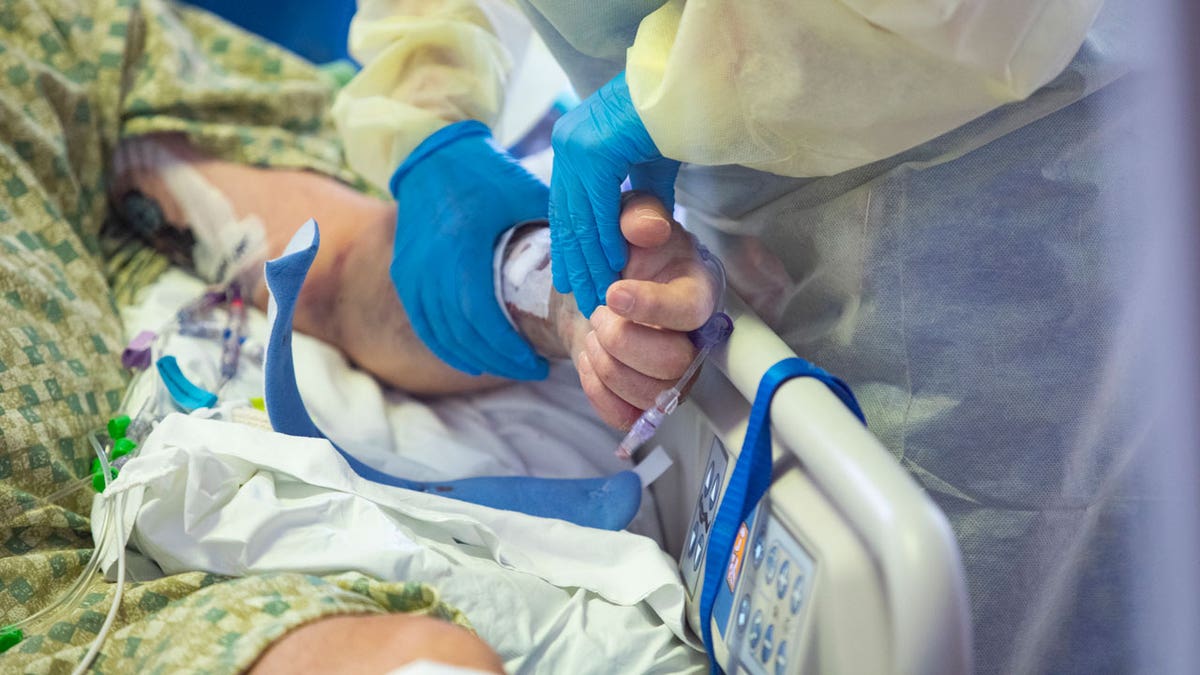 nurse holds COVID patient's hand