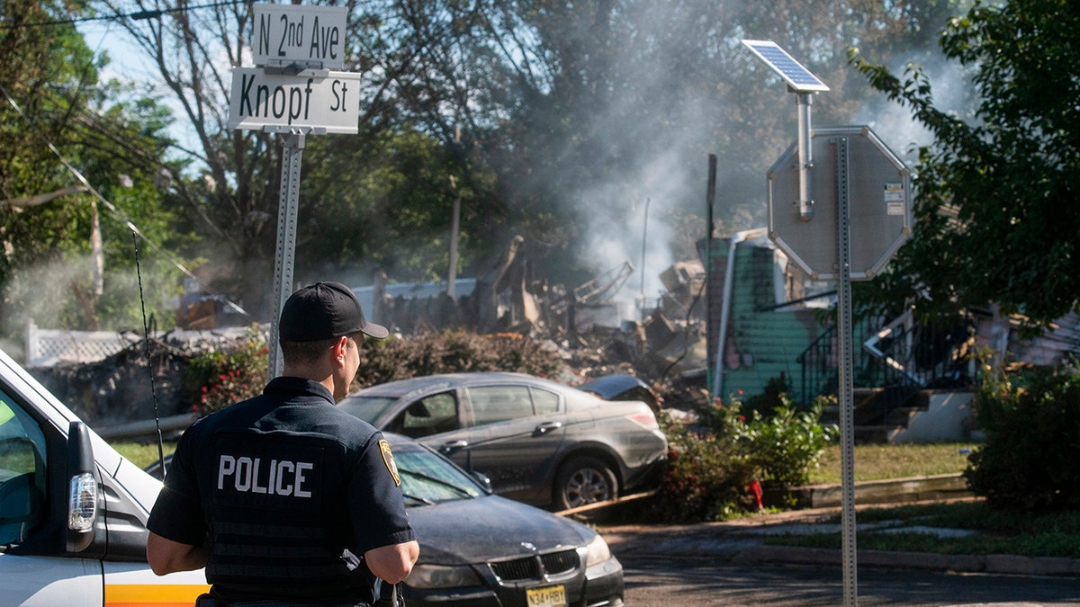 A Manville Police Officer stands guard near the remains of a house that exploded due to severe flooding from Tropical Storm Ida in Manville, NJ., Friday. Dozens of people in five states died as storm water cascaded into people’s homes and engulfed automobiles, overwhelming urban drainage systems never meant to handle so much rain in such a short time.