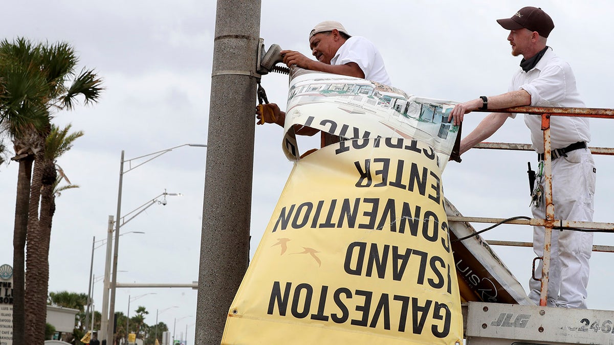Workers remove banners from a post in front of Landry's Seafood House in Galveston, Texas, Monday, Sept. 13, 2021, as residents and business prepare for Tropical Storm Nicholas. (Jennifer Reynolds/The Galveston County Daily News via AP)
