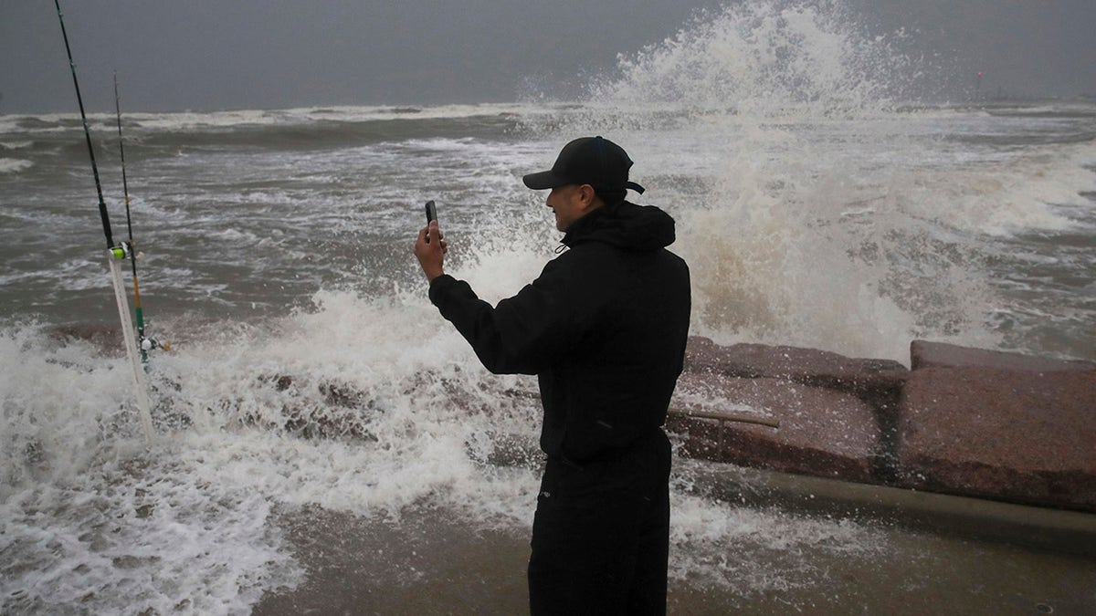 Frank Rivera streams a Facebook live as he fishes with a friend while Tropical Storm Nicholas heads toward the Texas coast, Monday, Sept. 13, 2021, along the seawall in Galveston, Texas. (Jon Shapley/Houston Chronicle via AP)