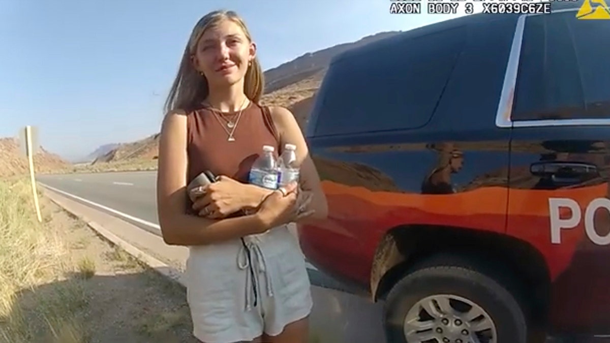 Gabby Petito appears upset while carrying water bottles in a red top in Moab