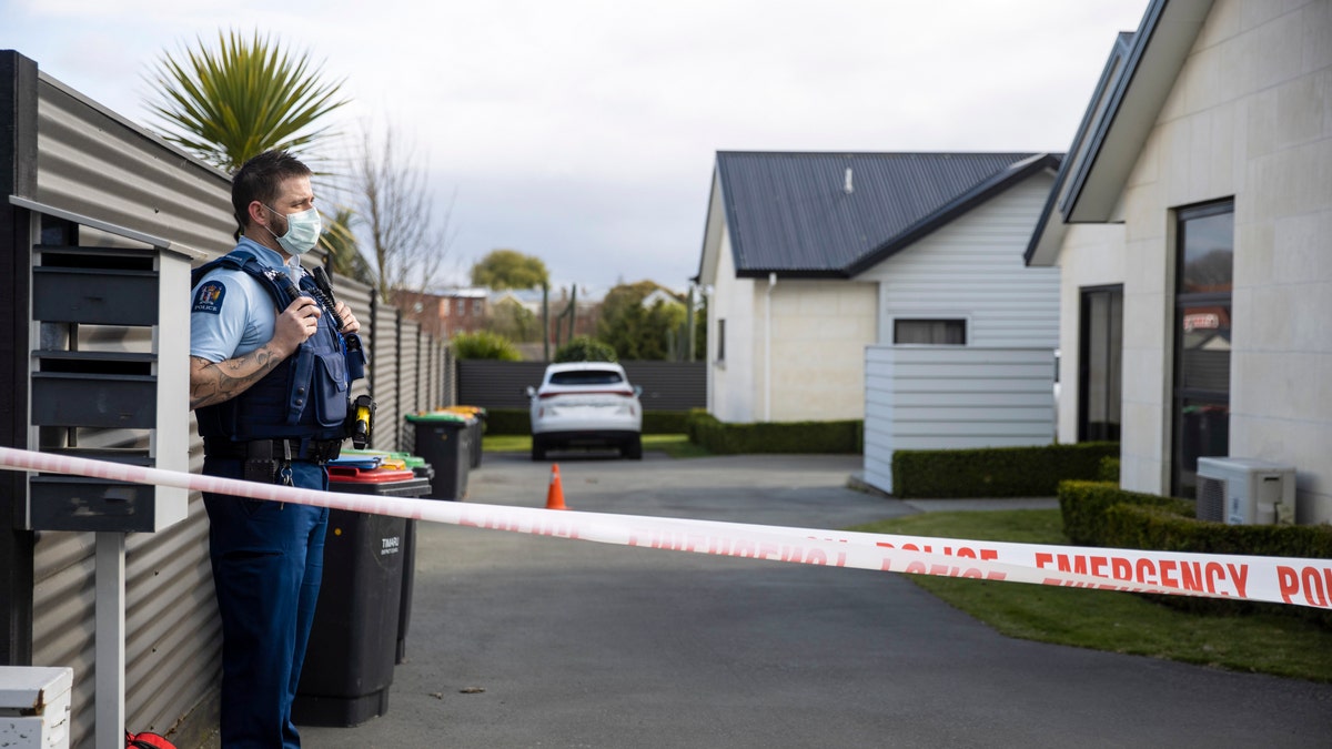 A police officer stands in the driveway of a house where three children were found dead in the South Island town of Timaru, New Zealand, Friday, Sept. 17, 2021.
