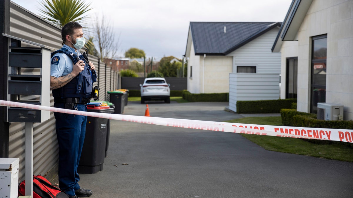A police officer stands in the driveway of a house where three children were found dead in the South Island town of Timaru, New Zealand, Friday, Sept. 17, 2021.