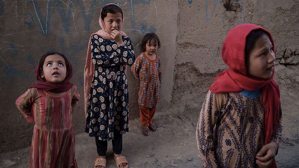 Afghan girls look up and listen as a neighbour describes when two men fell from a U.S. Air Force C-17 taking off from Kabul’s International Airport on Aug. 16 and landed on the rooftop of his house in Kabul, Afghanistan, Friday, Sept. 17, 2021. (AP Photo/Felipe Dana)
