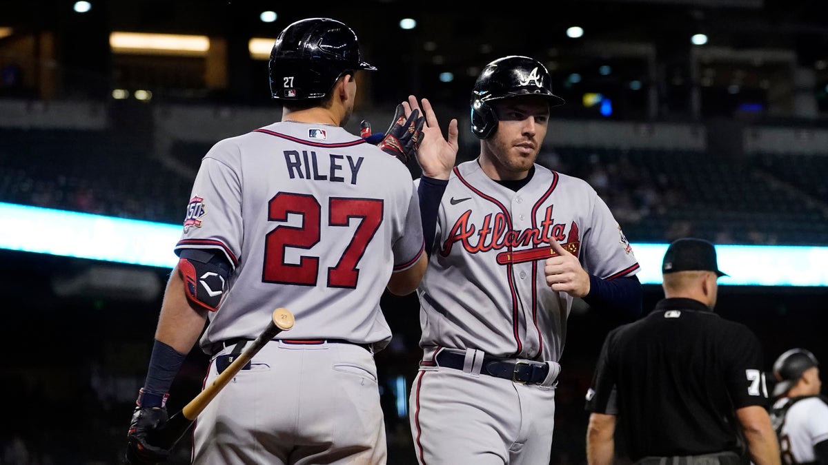 Atlanta Braves' Freddie Freeman high fives Austin Riley (27) after scoring on a double hit by Ozzie Albies during the fifth inning of a baseball game against the Arizona Diamondbacks, Monday, Sept. 20, 2021, in Phoenix. 