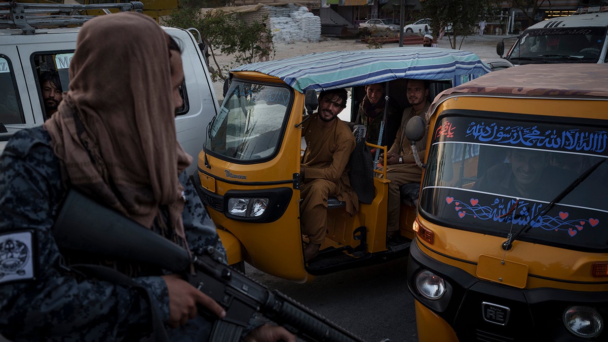 Afghan drivers and passengers stuck in a traffic jam look at Taliban fighters riding in the back of a vehicle in Kabul, Afghanistan, Monday, Sept. 20, 2021. (AP Photo/Felipe Dana)