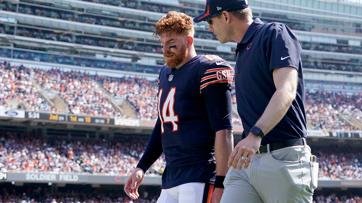 Chicago Bears quarterback Andy Dalton walks to the locker room with an unidentified trainer during the first half of an NFL football game against the Cincinnati Bengals Sunday, Sept. 19, 2021, in Chicago.