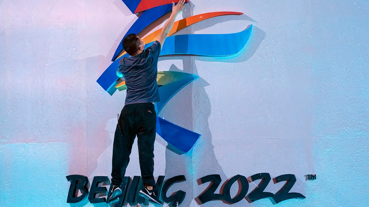 A crew member leaps to fix a logo for the 2022 Beijing Winter Olympics before a launch ceremony to reveal the motto for the Winter Olympics and Paralympics in Beijing, Friday, Sept. 17, 2021.