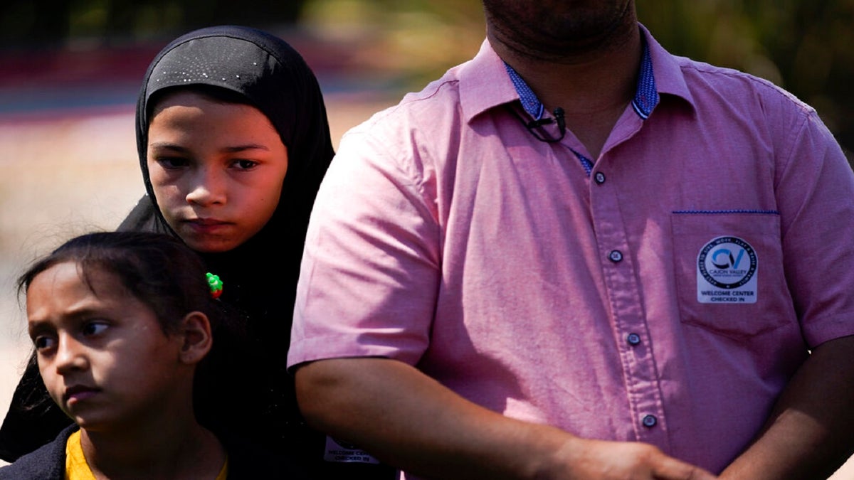 Palwasha Faizi, 10, above left, stands behind her sister, Parwana Faizi, 7, and alongside her father, Mohammad Faizi, during a news conference Thursday in El Cajon, Calif.?