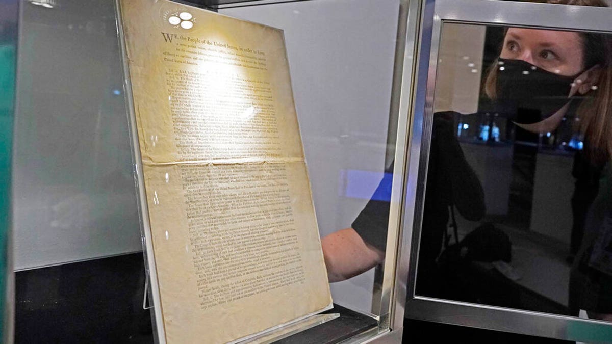 Ella Hall, a specialist in Books and Manuscripts, at Sotheby's, in New York, places a 1787 printed copy of the U.S. Constitution in its display case. It's the only copy that remains in private hands and has an estimate of $15 million-$20 million. (AP Photo/Richard Drew)
