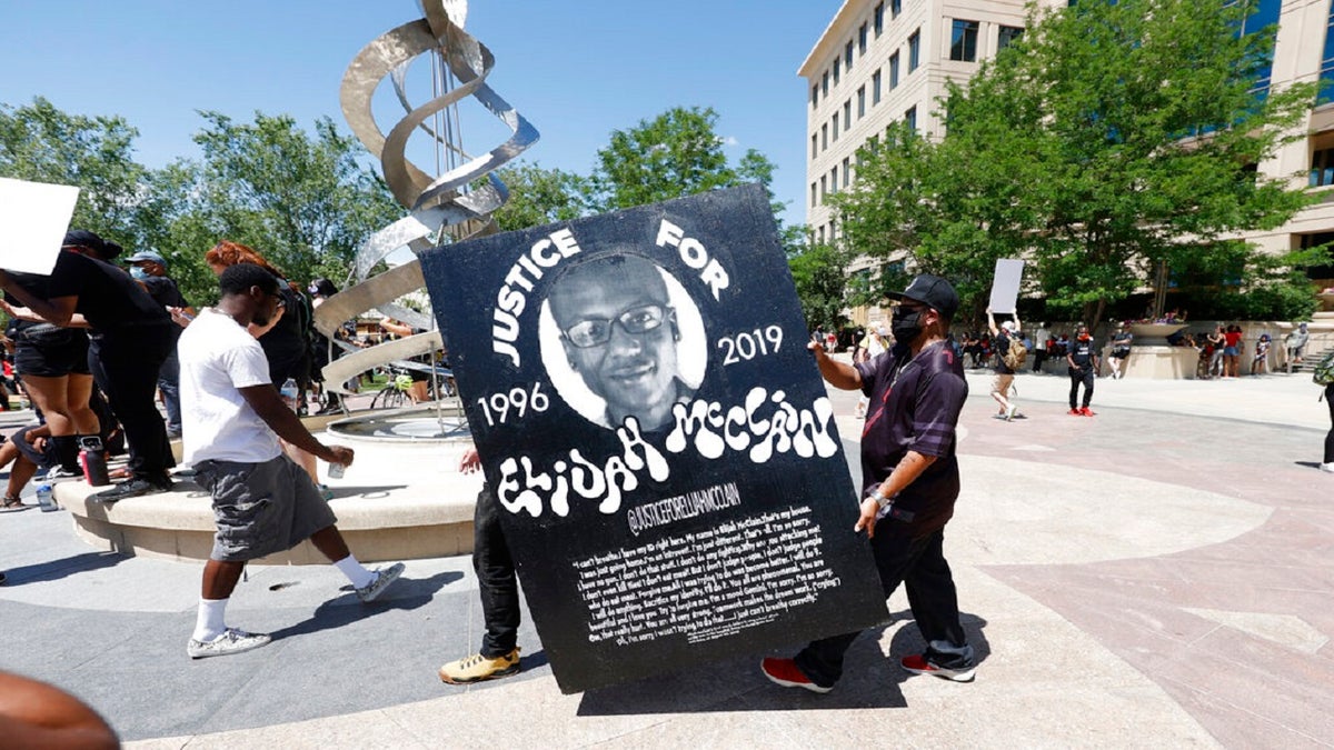 Demonstrators carry a giant placard during a rally and march over the death of Elijah McClain outside the police department in Aurora, Colorado, on June 27, 2020.