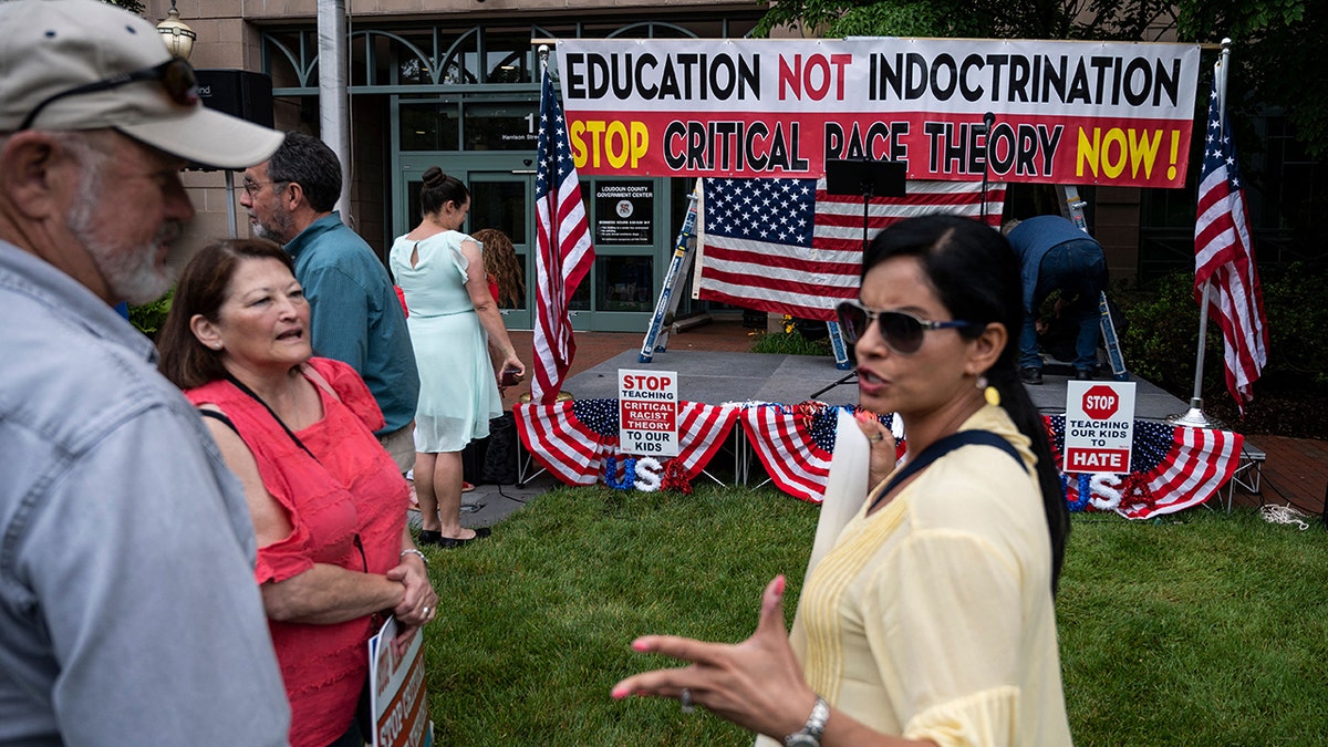 People talk before the start of a rally against "critical race theory" (CRT) being taught in schools at the Loudoun County Government center in Leesburg, Virginia 