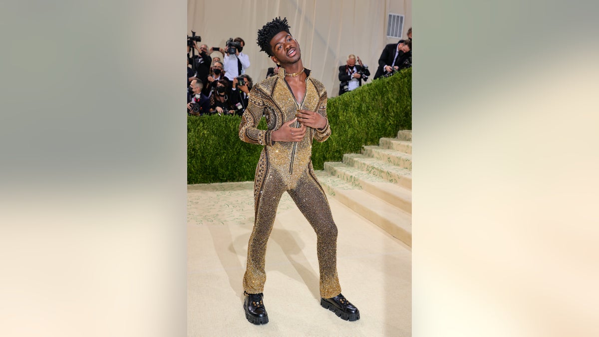 Lil Nas X in a black and gold bodysuit on the red carpet for the 2021 Met Gala in New York City. 