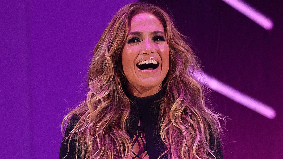 Jennifer Lopez in a black top with curly hair at the 2021 MTV Video Musics Awards smiling on stage