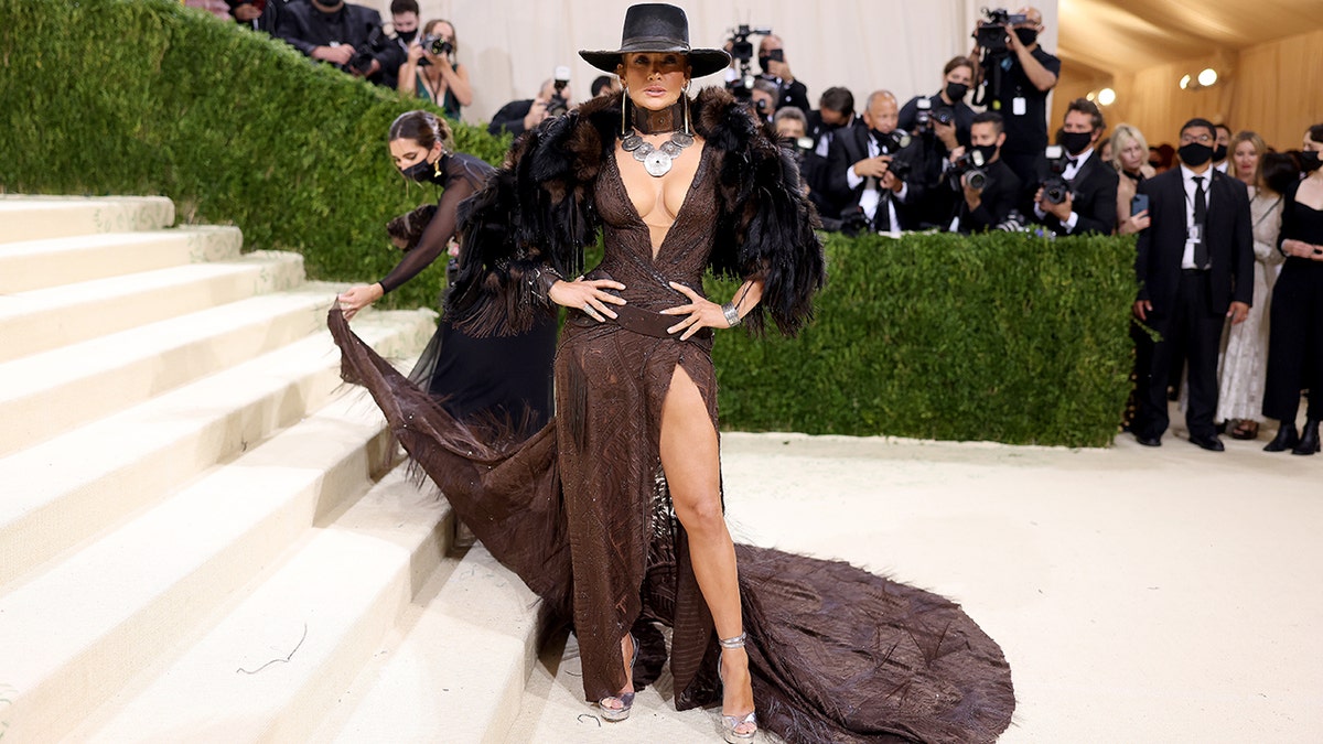 Jennifer Lopez goes with the cowboy hat and Western look in a flowing brown gown with a high-thigh slit and an elegant train.