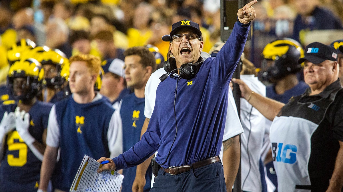 Michigan coach Jim Harbaugh signals a Michigan first down on the sideline during the fourth quarter of the team's NCAA college football game against Washington in Ann Arbor, Mich., Saturday, Sept. 11, 2021.