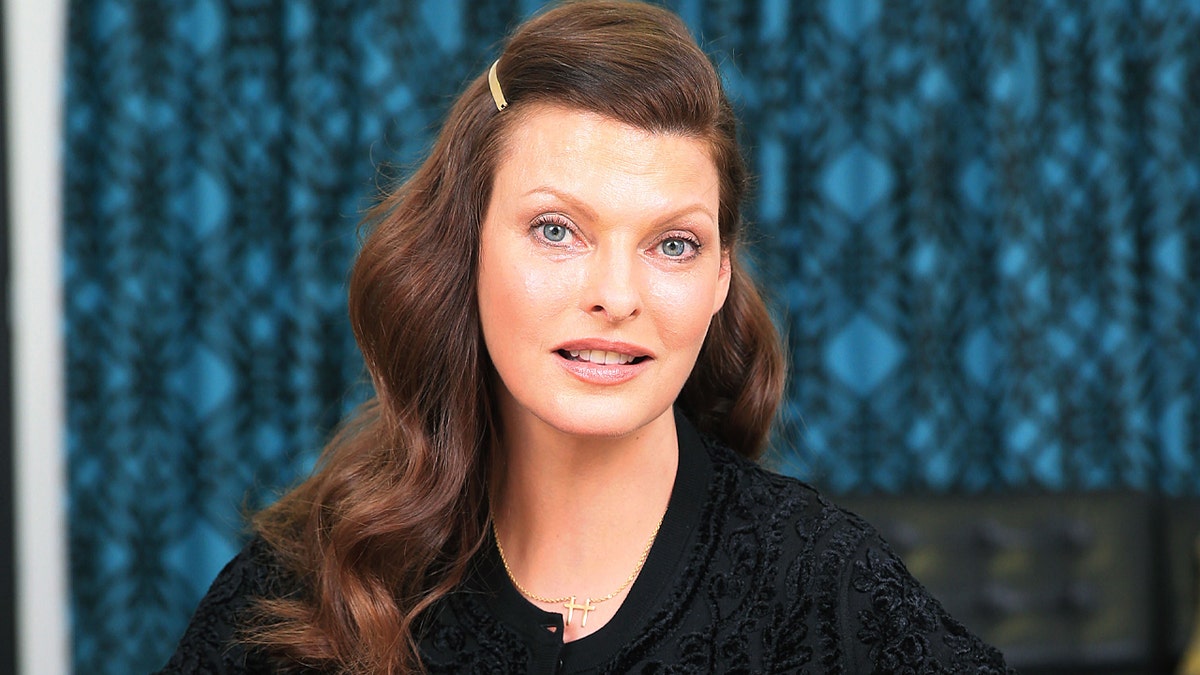 Linda Evangelista in a black shirt has her hair pinned up on one side