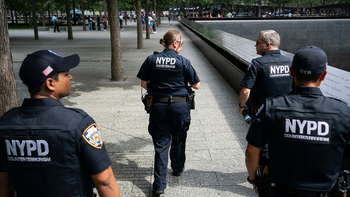 FILE –  Aug. 16, 2021: NYPD officer Michael Dougherty, a 25-year veteran, second from right, patrols with his colleagues beside the south reflecting pool of the 9/11 Memorial &amp; Museum where names of his deceased colleagues and friends are displayed.