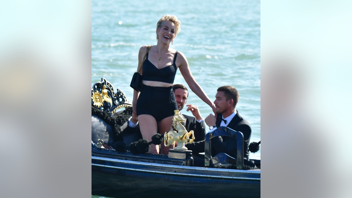 63-year old American Actress Sharon Stone looks stunning in her tight black outfit while out on a boat with two male models in Venice. The ‘Basic Instinct’ star showed off her legs during her glamorous shoot for the fashion brand Dolce and Gabbana.