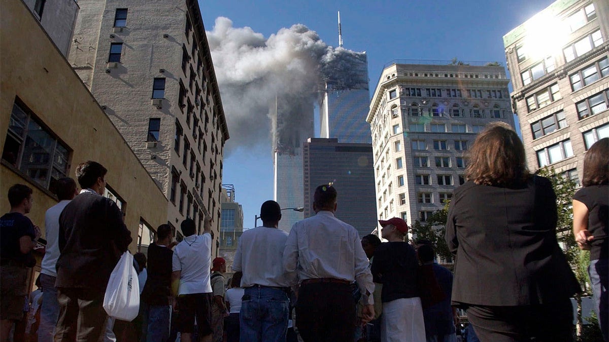 Pedestrians in lower Manhattan watch smoke billow from New York's World Trade Center on Tuesday, 9/11/01