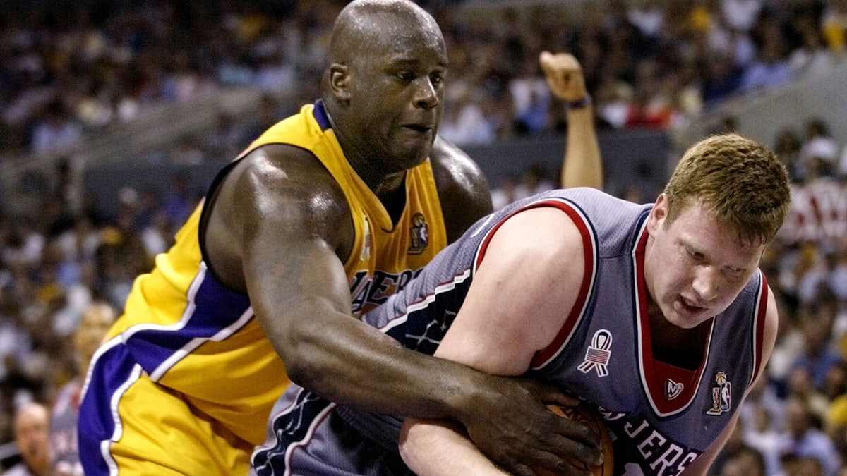 Los Angeles Lakers' Shaquille O'Neal (L) reaches from behind to latch onto the ball and New Jersey Nets' Todd MacCulloch during Game 1 of the NBA Finals June 5, 2002 in Los Angeles. 